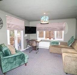 A snug with a sofa and armchair and a television at The Nest Lodge 55 Grantham