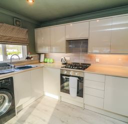 A kitchen with a washing machine, stove, and sink at The Nest Lodge 55 in Grantham