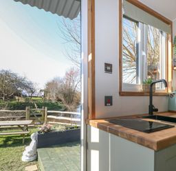 A kitchen with a window and stove at Salt Haven Shepards Hut in Pevensey