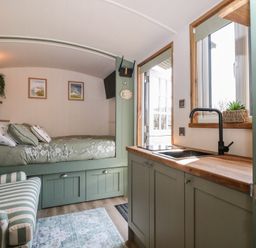 A bedroom with a bed and kitchenette at Salt Haven Shepards Hut Pevensey