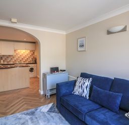 A living room with a blue sofa and kitchen area at 6 Dartmouth House in Dartmouth