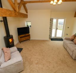 A living room with sofas and a television at Dairy Cottage in Oxwich