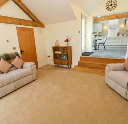 A living room with sofas and a media console at Dairy Cottage in Oxwich