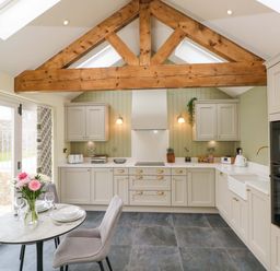 A kitchen with cabinets and a table set at Dairy Cottage in Oxwich