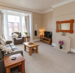 A living room with a sofa, armchair, coffee table and television at Time Out in Whitby