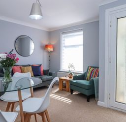 A living room with a glass table and seating at The Arches in Torquay