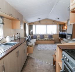 A living room with a sofa and kitchen area at Ger Y Mor in New Quay