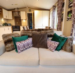 A living room with a couch and kitchen area at 108 Fox Burrow Hang, Great Yarmouth