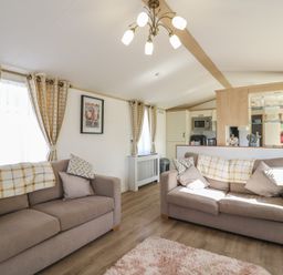 A living room with sofas and kitchen counter at 2 bed Caravan Stowmarket