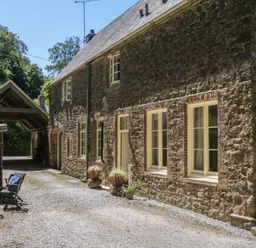 A stone house with outdoor furniture at Lukesland Wing in Ivybridge