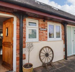 An entrance with a wooden door and a sign at The Coach House in Dorchester