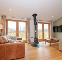 A living room with a wood stove and double doors at 4 Southern Place in Dobwalls