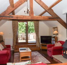 A living room with a sofa, coffee table, and television at The Cottage in Sampford Courtenay