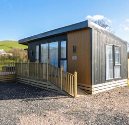 A cabin with a deck and fenced area at Dawn's Rest in Nantmel near Rhayader