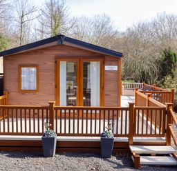 A lodge with a deck and railings at Gardeners Lodge in 