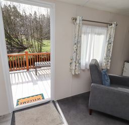A living room with a door leading to a deck at Gardeners Lodge