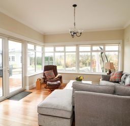 A conservatory with a sofa and armchair at Sunnyside in River Chapel