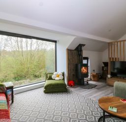 A living room with a wood stove and sofa at Trwyn Cam in Brynrefail near Llanberis