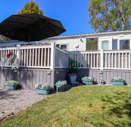 A caravan with a deck and umbrella at Grosvenor 10 Llanarmon-Yn-Ial