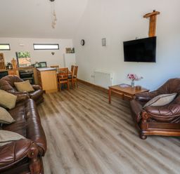 A living room with a sofa and dining area at Brookview Kingfisher in Haverfordwest