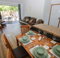 A dining room with a table set for dinner and a sofa at Brookview Kingfisher in Haverfordwest