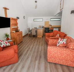 A living room with a television and dining area at Brookview Goldfinch in Haverfordwest