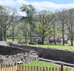 A view of trees and stone walls with a railway track at Pandora in Holmrook