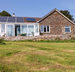 A house with solar panels and a wall at Tregoning in Lostwithiel
