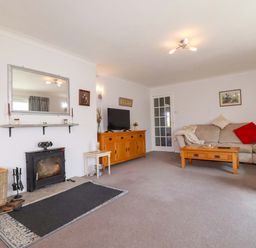 A living room with a sofa, coffee table, and fireplace at Tregoning in Lostwithiel