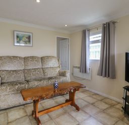 A living room with a sofa and a wooden table at Watersmeet - 85 @ Park Avenue Holiday Village, Leysdown-On-Sea, Kent