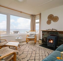 A living room with a sea view and a fireplace at Wootton Gray in Penzance