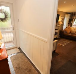 A hallway with a door, rug, lamp, and view of a living room at Jodene Lodge, Redwood 2 in Bowness-On-Windermere