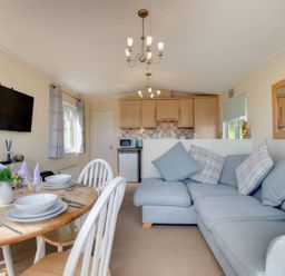 A living room with dining area and kitchen appliances at Pet-friendly lodge with hot tub near the coast