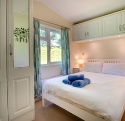 A bedroom with a bed, wardrobe, and window at Pet-friendly lodge with hot tub near the coast