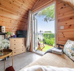 An indoor space with a fridge, TV, and couch at Peaceful pod with bay views, walk to 3 beaches in St Ives