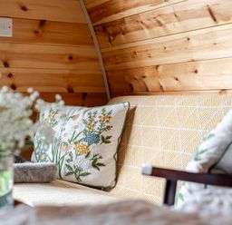 A couch with a decorative pillow and flower arrangement at Peaceful pod with bay views, walk to 3 beaches St Ives