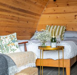 A bedroom with a sofa, bed, and champagne at Peaceful pod with bay views, walk to 3 beaches St Ives