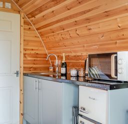 A kitchen with a sink, microwave, fridge, and champagne at Peaceful pod with bay views, walk to 3 beaches St Ives