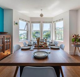 A dining room featuring a wooden table set with plates and glasses at tbc