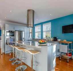 A kitchen with a cooking island and stools at tbc in 