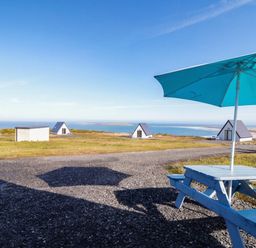 A picnic table with an umbrella and cabins near the beach at Cabin 9 Inish Beag, Gortahawk