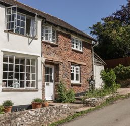 An exterior view of a stone cottage with windows and a door at Upper Frogpool Cottage Crediton