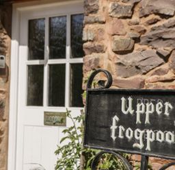 An entrance with a stone wall and door at Upper Frogpool Cottage in Crediton