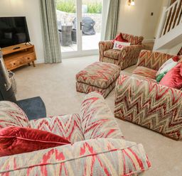 A living room with sofas and a television at Barley Cottage in Oxwich