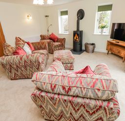 A living room with sofas and a wood stove at Barley Cottage in Oxwich