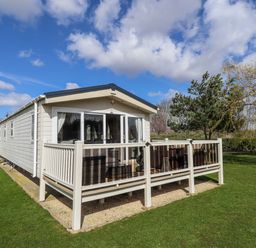 A house with a deck and railing surrounded by grass at 13 The Lakes Mablethorpe