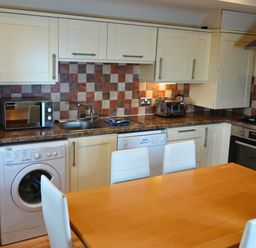 A kitchen with appliances and a dining table at Bracken Lodge in Finlakes Holiday Park near Chudleigh