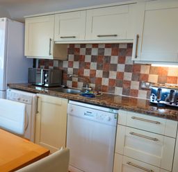 A kitchen with appliances and a dining table at Bracken Lodge Finlakes Holiday Park near Chudleigh