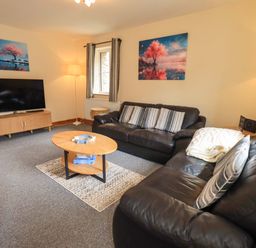 A living room with a sofa and television at 4 Mellbecks Mews in Kirkby Stephen