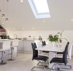 A kitchen with bar stools and a dining table at Meadow Retreat in Bodmin
